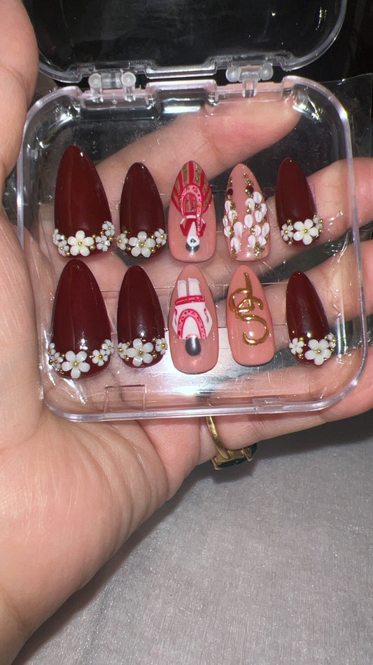 Set of red and gold nail art designs in a clear case held by a person.